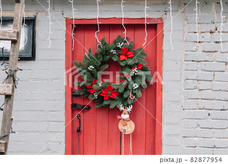 Red wooden door decorated with Christmas wreath. 82877954