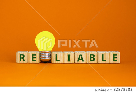 Reliable symbol. Wooden cubes with the word reliable. Yellow light bulb. Beautiful orange background, copy space. Business and reliable concept. 82878203