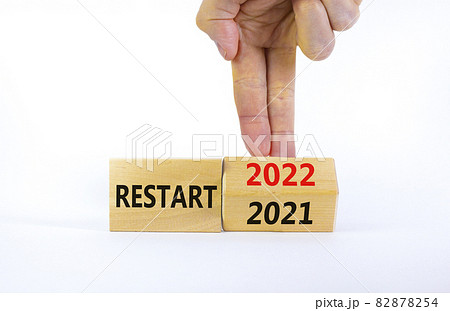 2022 restart new year symbol. Businessman turns a wooden cube and changes words 'Restart 2021' to 'Restart 2022'. Beautiful white background, copy space. Business, 2022 restart new year concept. 82878254