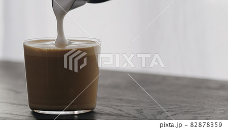 making cappuccino in tumbler glass on black aok table 82878359