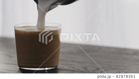 making cappuccino in tumbler glass on black aok table 82878361