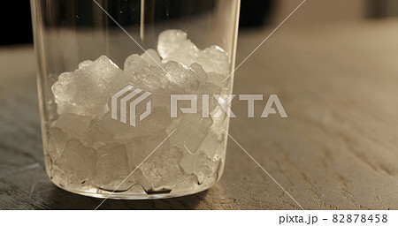 pour crushed ice in tumbler glass on oak table closeup 82878458