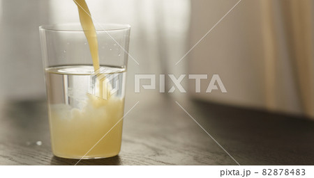 pour orange juice in sparkling water in tumbler glass on black wood table with copy space 82878483