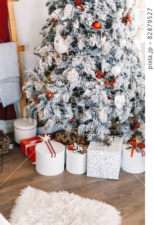 Beautiful Christmas tree with gift boxes in bright white living room. 82879527