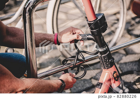 User safely parking electric scooter and locking it to a fence. Eco friendly green modern urban mobility concept of sharing transportation with electric scooters for rent in Ljubljana, Slovenia 82880226