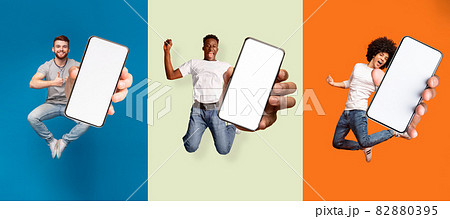 Satisfied happy excited diverse people jumping, have fun and show smartphone with blank screen 82880395