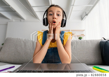 Surprised girl sitting at desk, having videocall wearing headset 82880658