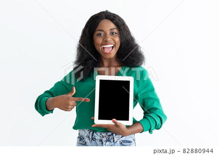 Emotional black woman pointing at digital tablet with empty screen Emotional black woman pointing at digital tablet with empty screen 82880944