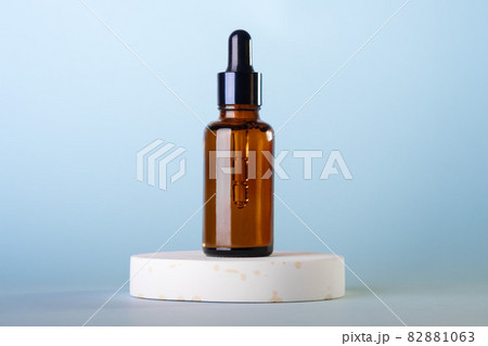 Amber glass dropper cosmetic bottles, white podium on pastel blue background. Scene with geometric shapes. Showcase. 82881063