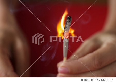 Burning match in hand on red background Burning match in hand on red background 82881117
