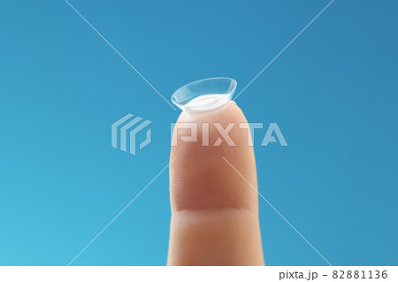 Soft contact lens on female finger on blue background Soft contact lens on female finger on blue background 82881136