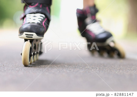 Woman is rolling on black beautiful rollerblades on asphalt closeup Woman is rolling on black beautiful rollerblades on asphalt closeup 82881147