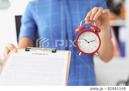 Businesswoman holds red alarm clock and contract on clipboard 82881148