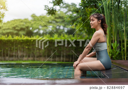 woman sitting on edge of swimming pool woman sitting on edge of swimming pool 82884697