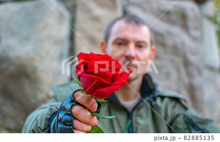 the guy's outstretched hand holds a rose flower 82885135