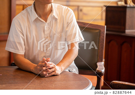 手を組んで話をする男性　椅子に座って話をする人 82887644
