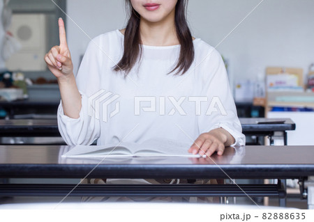 デスクで本を開いてサインを送る女性　サインを送る人 82888635