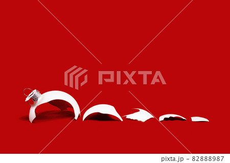 White broken glass bauble on red Christmas background. White broken glass bauble on red Christmas background. 82888987