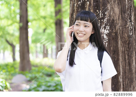大木の側で電話をする少女 大木の側で電話をする少女 82889996