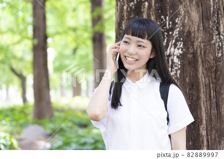 大木の側で電話をする少女 大木の側で電話をする少女 82889997
