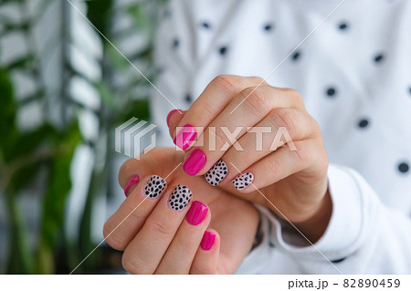 Manicured female hands with stylish pink nails and design. Trendy modern design manicure. Gel nails. Skin care. Beauty treatment. Nail care. Trendy colors 82890459