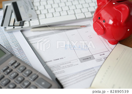 Invoice with paid stamp with bank cards and piggy bank on table 82890539