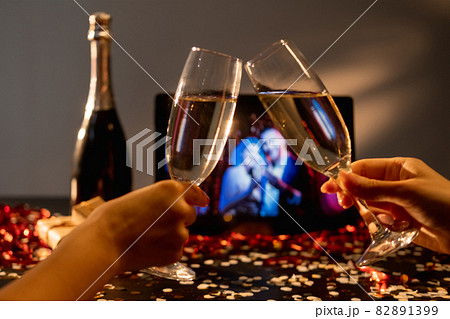 Christmas party. Online greeting. Video conference. Festive female friends cheering glass champagne defocused congrats on tablet computer in holiday home interior. Christmas party. Online greeting. Video conference. Festive female friends cheering glass champagne defocused congrats on tablet computer in holiday home interior. 82891399