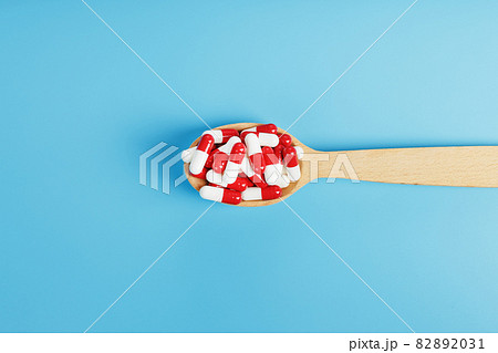 Red and white pill capsules on a blue background. Red and white pill capsules on a blue background. 82892031