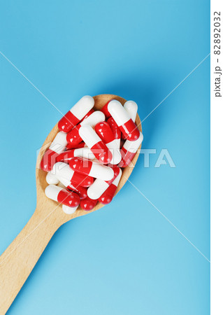 Red and white pill capsules on a blue background. Red and white pill capsules on a blue background. 82892032
