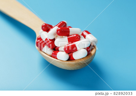 Red and white pill capsules on a blue background. Red and white pill capsules on a blue background. 82892033