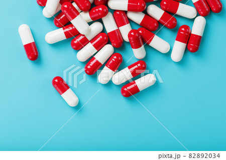 A handful of Red and white pill capsules on a blue background. Free space Top view A handful of Red and white pill capsules on a blue background. Free space Top view 82892034