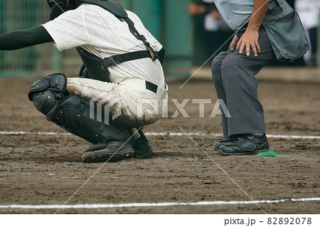 野球の試合中にピッチャーの投げた球を受けようとするキャッチャーと判定をくだそうとする球審 82892078