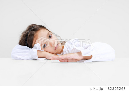 Portrait of beuatiful school girl sitting and looking at camera isolated on white background. Portrait of beuatiful school girl sitting and looking at camera isolated on white background. 82895263