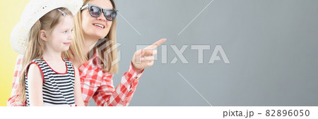 Mother in sunglasses showing her finger to little girl in hat Mother in sunglasses showing her finger to little girl in hat 82896050