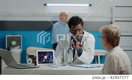 Young doctor analyzing virus animation on tablet with old woman Young doctor analyzing virus animation on tablet with old woman 82897377