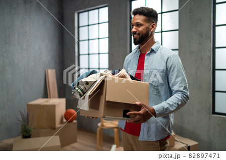 Happy young man holding packing boxes moving home, new living concept. Happy young man holding packing boxes moving home, new living concept. 82897471
