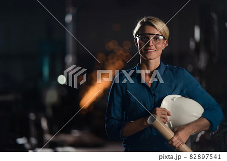 Portrait of happy young industrial woman engineer looking at camera indoors in metal workshop. Portrait of happy young industrial woman engineer looking at camera indoors in metal workshop. 82897541