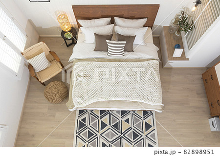 Interior of modern bedroom with white mattress, wooden floor, armchair and brown pillow setting. Top view of spacious bedroom. Interior of modern bedroom with white mattress, wooden floor, armchair and brown pillow setting. Top view of spacious bedroom. 82898951