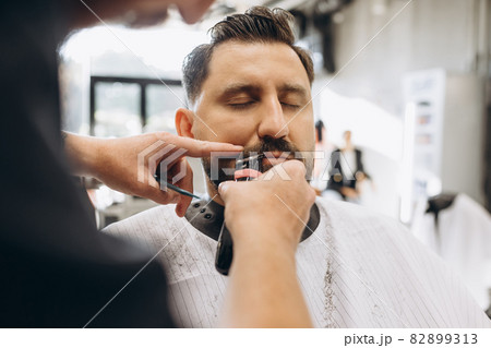 Professional barber, clipper making hair cut to customer, young man at barbershop. Beauty, selfcare, style, fashion and male cosmetics concept. 82899313