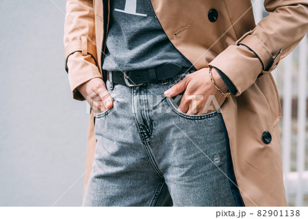 Fashionable woman in a black shirt and beige raincoat with trendy bracelet on her hand. Fashionable woman in a black shirt and beige raincoat with trendy bracelet on her hand. 82901138