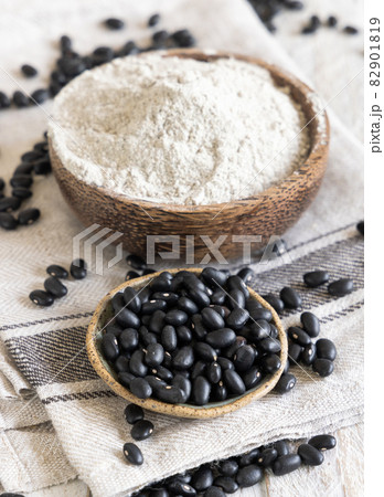Ceramic bowls with black beans flour with a wooden spoon 82901819