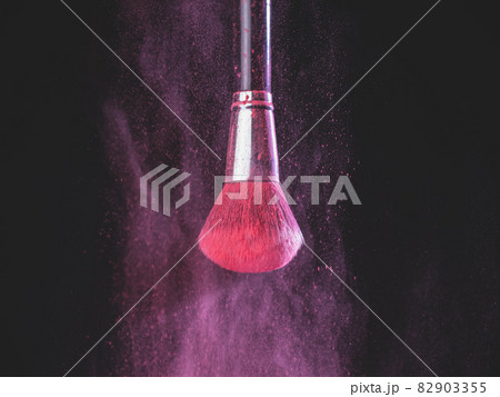 Make-up brush with pink powder explosion on black background Make-up brush with pink powder explosion on black background 82903355