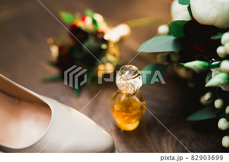 Pair of elegant and stylish bridal shoes with wedding rings and a bouquet of roses and other flowers 82903699