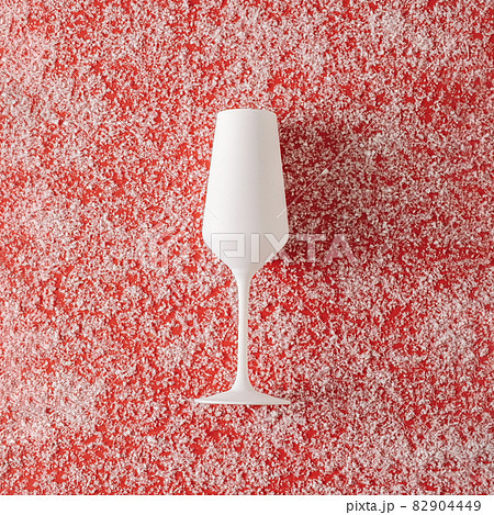 Pure white champagne glass over a red Christmas background Pure white champagne glass over a red Christmas background 82904449