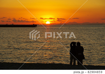 海岸で沈む夕日を眺めるカップル 海岸で沈む夕日を眺めるカップル 82904859