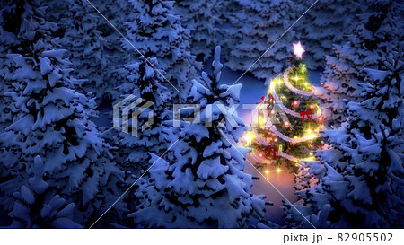 lightened christmas tree surrounded by snow-covered pine trees at night 82905502