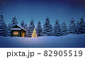 lightened christmas tree in front of wooden cabin in snow at night with pine trees in background 82905519