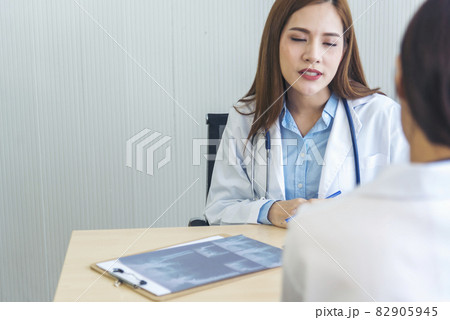 Two asian women doctors discuss meeting doctor's office medical clinic looking x-ray film consulting patient disease. Asian medical lab young women talking together discussing healthcare teamwork 82905945