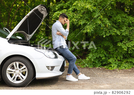 Puzzled arab man standing by open car hood 82906292
