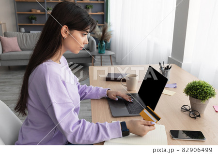 Millennial lady using computer and credit card at home 82906499